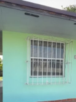 Front window of a mint-green South Florida house — Prop Hunters project